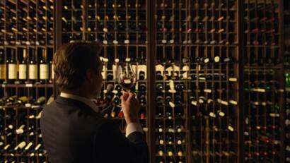 Sommelier evaluating a glass of wine in the cellar with Bodegas Muñoz wines on the shelves